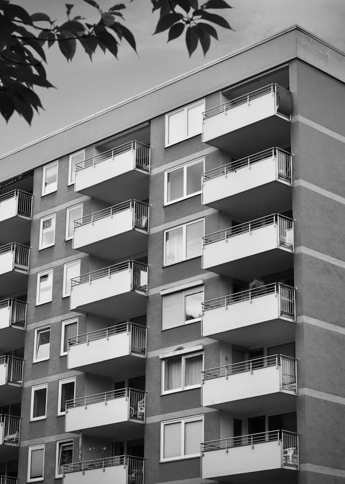 about-01 Monochrome photo of a modern apartment building with balconies, showcasing urban architecture.
