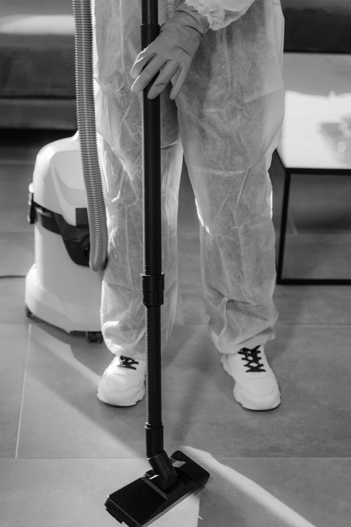 services-02 Monochrome image of a person in PPE vacuuming indoors. Suitable for COVID-19 and hygiene concepts.